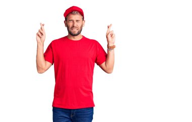 Tişört giyen ve şapka takan genç sarışın adam umut ve gözler kapalı gülümseyerek el sallıyor. Şans ve batıl inançlar. 