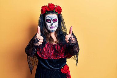 Genç bir kadın ölü kostümünü giyip sarıyı onaylıyor. Elleriyle olumlu bir jest yapıyor. Gülümsüyor ve başarı için seviniyor. kazanan jest. 