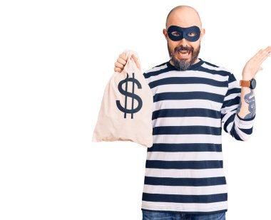Hırsız maskesi takan genç yakışıklı bir adam. Elinde dolar sembollü para çantası var. Zaferi kutluyoruz. 