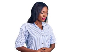 Genç Afro-Amerikalı kadın, hazımsızlık, acı veren hastalıklar yüzünden elleri karnında gündelik giysiler giyiyor. Ağrı kavramı. 