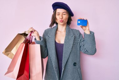 Bere takan, alışveriş torbası takan ve kameraya bakıp öpüşen güzel bir kadın. Sevimli ve seksi. aşk ifadesi. 