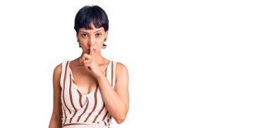 Kısa saçlı, kısa saçlı, yaz kıyafeti giyen genç esmer kadın sessiz olmak istiyor. sessizlik ve gizli konsept. 