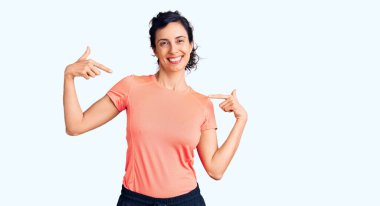 Genç ve güzel İspanyol kadın spor giysisi giyiyor. Kendine güveni tam görünüyor. Kendini gururlu ve mutlu bir şekilde gösteriyor.. 