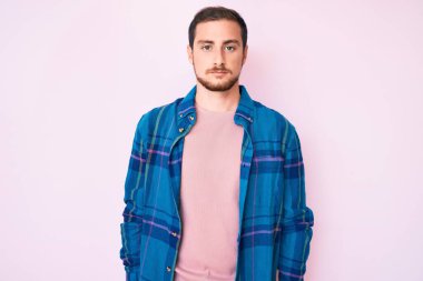 Gündelik kıyafetler giyen genç yakışıklı adam yüzünde ciddi bir ifadeyle rahatlamış. Basit ve doğal bir şekilde kameraya bakıyorsun.. 