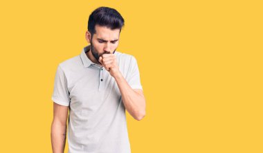 Sakallı, sıradan polo giyen, kendini kötü hisseden ve soğuk algınlığı veya bronşitin belirtisi olarak öksüren genç yakışıklı bir adam. sağlık hizmeti kavramı. 