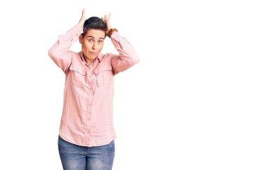 Kısa saçlı, günlük kıyafetler giyen, tavşan kulağı yapan, avuçlarıyla alaycı ve şüpheci görünen genç bir kadın. Paskalya tavşanı konsepti. 