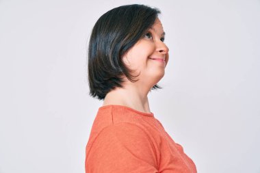 Esmer, düşük sendromlu bir kadın, günlük giysiler giyip yan tarafa bakıyor, rahat bir poz veriyor, kendine güvenen bir gülümsemesi var.. 