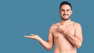 Mayo giyen genç ve yakışıklı adam hayret içinde kameraya gülümserken eliyle ve parmağıyla işaret ediyor.. 