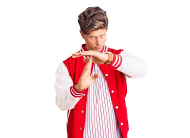 Beyzbol üniforması giyen yakışıklı genç adam. Elleriyle jest yapıyor, hayal kırıklığına uğramış ve ciddi bir yüz ifadesi takınıyor. 