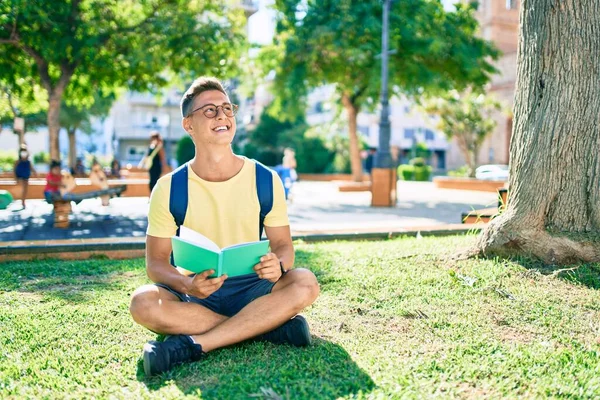 Üniversite Kampüsündeki Çimlerin Üzerinde Oturmuş Kitap Okuyan Genç Spanyol Öğrenci — Stok fotoğraf