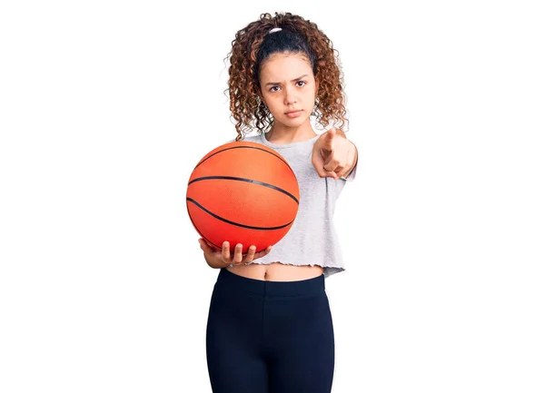 漂亮的小女孩 拿着篮球 用手指着相机 对着你 自信地摆出一副严肃的姿势 — 图库照片