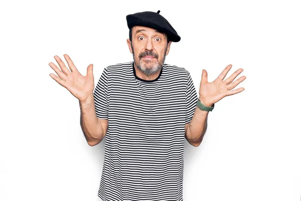 Beyaz arka planda çizgili tişört ve Fransız beresi giyen orta yaşlı yakışıklı bir adam. Hiçbir şeyden habersiz, kolları açık, hiçbir fikri yok ve şüpheli bir yüzü var..