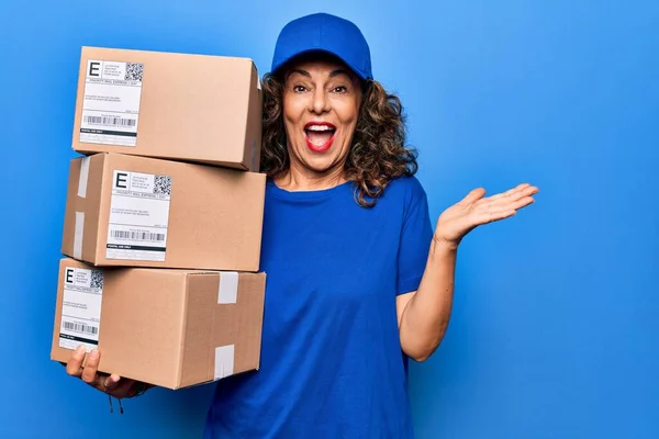 Mulher Meia Idade Bela Entrega Segurando Pacotes Sobre Fundo Azul — Fotografia de Stock