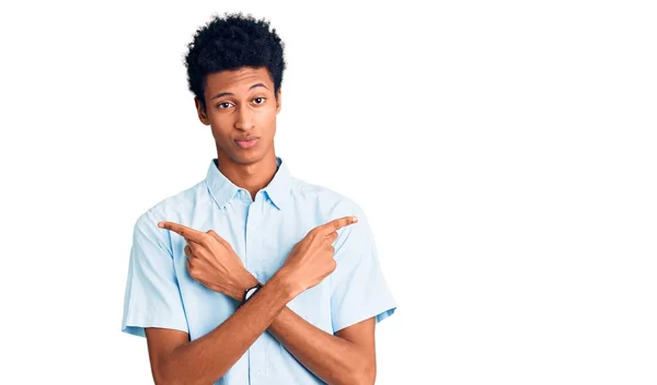 若いアフリカ系アメリカ人の男性は 指で両側を指してカジュアルな服を着て 異なる方向に反対 — ストック写真