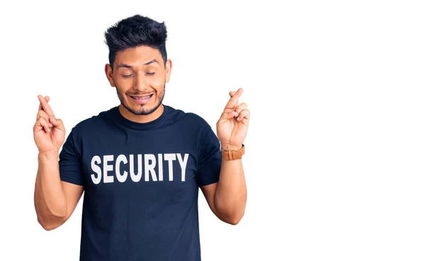 Όμορφος Λατινοαμερικάνος Νεαρός Που Φοράει Μπλουζάκι Ασφαλείας Σταυρώνει Δάχτυλο Χαμογελώντας — Φωτογραφία Αρχείου