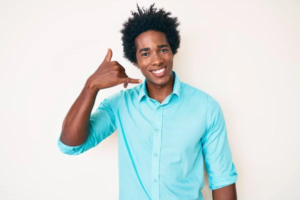 アフロの髪をしたハンサムなアフリカ系アメリカ人の男性は 電話で話すような手と指で電話のジェスチャーをして笑顔でカジュアルな服を着ています コミュニケーションの概念 — ストック写真