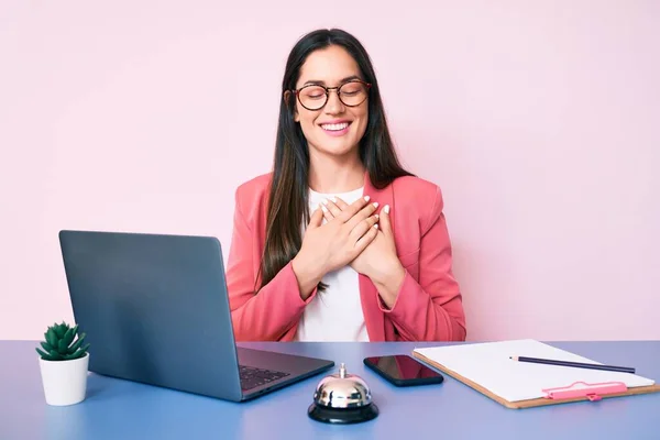 코카서스 여성이 접수원의 책상에 노트북으로 가슴을 미소짓고 얼굴에 감사를 표하는 — 스톡 사진