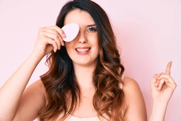 Joven Hermosa Morena Sosteniendo Esponja Maquillaje Sonriendo Feliz Señalando Con — Foto de Stock