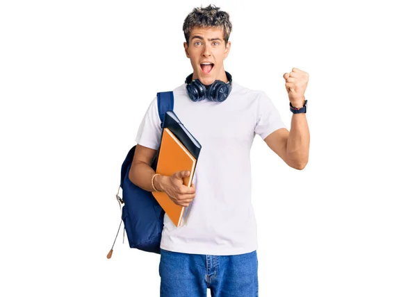 年轻英俊的男子拿着学生的背包和书本高喊着自豪 高举双臂庆祝胜利和成功 — 图库照片