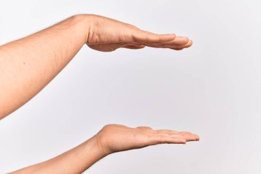 Beyaz tenli genç adam parmaklarını izole edilmiş beyaz arka planda gösteriyor aralarında kopya alanı tutuyor, her iki avuçla ölçüyor.