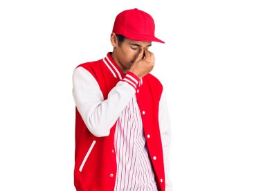 Beyzbol üniforması giyen Afrikalı genç bir Amerikalı burnu ve gözleri ovuşturmaktan yorgun düşmüş ve başı ağrıyormuş. Stres ve hüsran kavramı. 