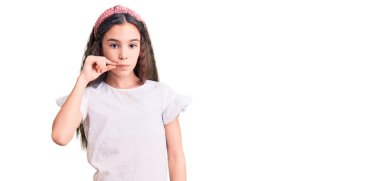 Beyaz tişört giyen tatlı İspanyol kız çocuğu ağzı ve dudakları parmaklarıyla fermuar gibi kapalı. gizli ve sessiz, tabu konuşması 