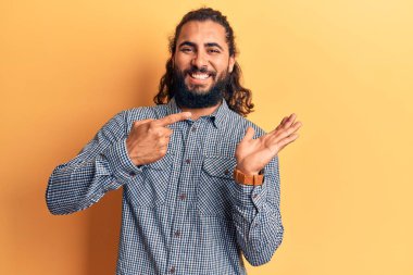 Gündelik giysiler giyen genç Arap adam kameraya hayret ediyor ve gülümsüyor.. 