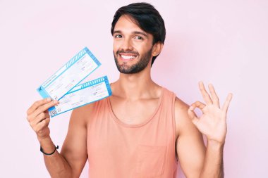 Yakışıklı İspanyol adam elinde biniş kartı tutuyor. Parmaklarıyla imza atıyor, gülümsüyor. Mükemmel bir sembol. 