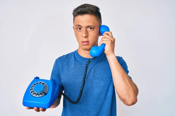 Ung Latinamerikansk Pojke Håller Vintage Telefon Ledtrådar Och Förvirrade Uttryck — Stockfoto