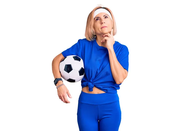 Молодая Блондинка Держит Футбольный Мяч Серьезное Лицо Думая Вопросе Рукой — стоковое фото