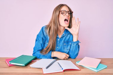 Masada oturmuş el ele tutuşup bağırarak çığlık atan genç sarışın kız. iletişim konsepti. 