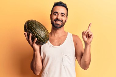 Karpuz tutan genç İspanyol adam gülümsüyor. 