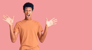 Genç afro-amerikan adam gündelik giysiler giyip çılgınlığı kutluyor ve başarıya hayret ediyor kolları açık ve gözleri açık heyecanla bağırıyor. Kazanan konsept 