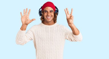 Genç İspanyol adam kulaklık kullanarak müzik dinliyor. Sekiz numaralı parmaklarıyla işaret ediyor ve gülümsüyor. Kendinden emin ve mutlu.. 
