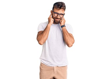 Gürültülü müzik sesi için günlük kıyafetler giyen ve kulaklarını parmaklarıyla kapatan İspanyol asıllı genç bir adam. sağır kavramı. 