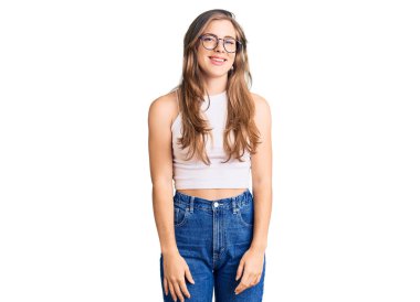 Yüzünde mutlu ve havalı bir gülümseme olan günlük kıyafetler ve gözlük takan güzel beyaz bir kadın. şanslı kişi. 