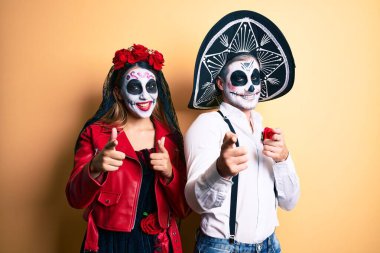 Ölü kostümü giyen çift, mutlu ve komik yüzlü parmaklarını kameraya doğrultuyor. iyi enerji ve titreşimler. 