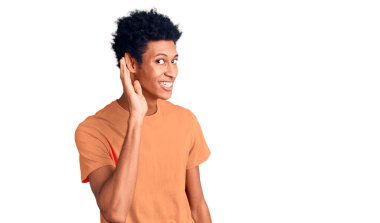 Genç Afro-Amerikan bir adam, günlük giysiler giymiş, ağzı kulaklarına varan bir gülümsemeyle dedikodu ve söylentileri dinliyor. Sağırlık kavramı. 