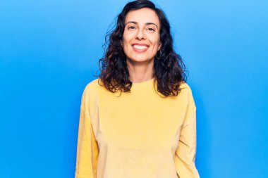 Genç, güzel, İspanyol bir kadın mutlu ve havalı bir gülümsemesi olan gündelik kıyafetler giyiyor. şanslı kişi. 