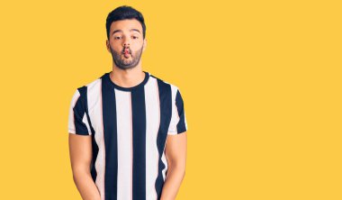 Çizgili tişört giyen genç yakışıklı İspanyol dudaklı balık suratı yapan çılgın ve komik bir jest. Komik ifade. 