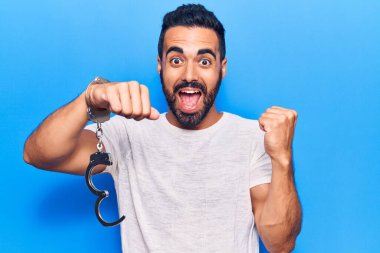 Tutsak kelepçeli İspanyol genç adam gururla bağırıyor, zaferi kutluyor ve başarıyı kollarını kaldırarak kutluyor. 