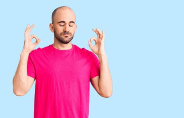 Gündelik tişört giyen genç yakışıklı adam rahatla ve gözleri kapalı gülümse parmaklarıyla meditasyon hareketi yapıyor. yoga konsepti. 