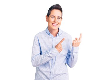 Kısa saçlı, iş kıyafetleri giyen, gülümseyen ve kameraya bakan iki eli ve parmakları yanda olan genç bir kadın.. 