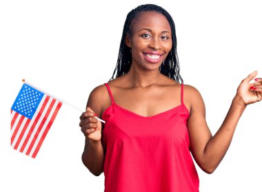Amerika Birleşik Devletleri bayrağını tutan genç Afro-Amerikan kadını mutlu bir şekilde gülümsüyor. 