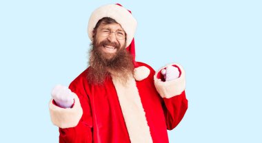 Uzun sakallı, yakışıklı kızıl saçlı, Noel Baba kostümü giyen çok mutlu ve heyecanlı, kolları havada, gülümseyen ve başarı için bağıran bir adam. kutlama konsepti. 
