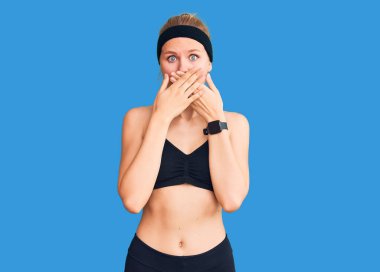 Spor kıyafetleri giyen genç ve güzel sarışın kadın yanlışlıkla elleri ile ağzını kapatırken şok oldu. gizli kavram. 