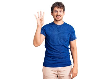 Kıvırcık saçlı, rahat giyinen, dört numaralı parmaklarıyla işaret eden, kendinden emin ve mutlu gülümseyen genç bir adam.. 