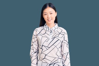 Genç, güzel Çinli bir kadın, mutlu ve havalı bir gülümsemesi olan sıradan bir tişört giyiyor. şanslı kişi. 