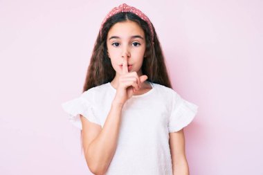 Günlük kıyafetler ve diyabet giyen tatlı İspanyol çocuk dudakları parmaklarıyla sessiz olmak istiyor. sessizlik ve gizli konsept. 