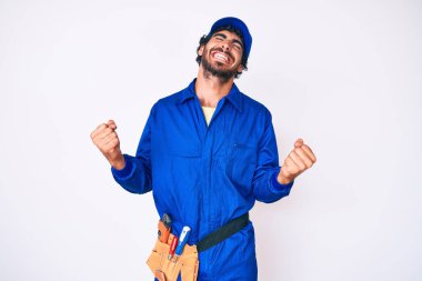 Kıvırcık saçlı ve ayı gibi giyinen yakışıklı genç adam. Çok mutlu ve heyecanlı. Kolları havada, gülümseyen ve başarı için çığlık atan kazanan jest yapıyor. kutlama konsepti. 